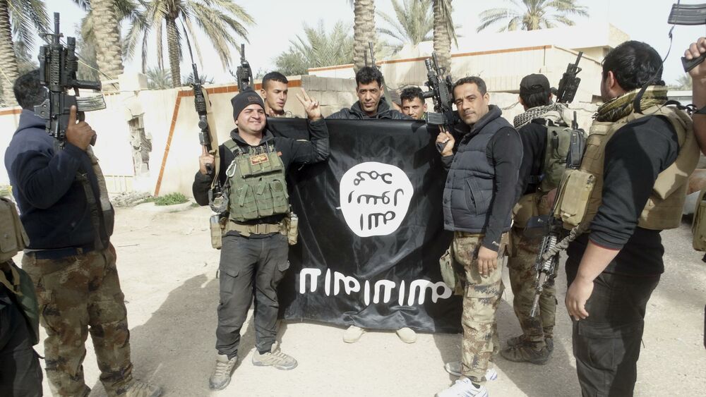 Iračke bezbednosne snage drže zastavu Islamske države dok slave oslobađanje jednog od gradova u Iraku