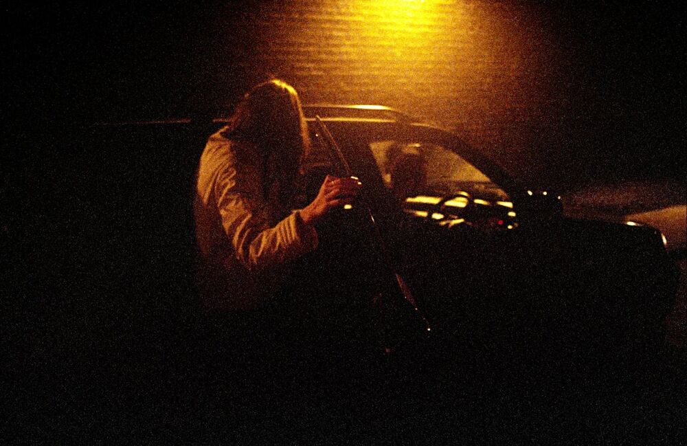 Devojka ulazi u automobil u mračnoj ulici 