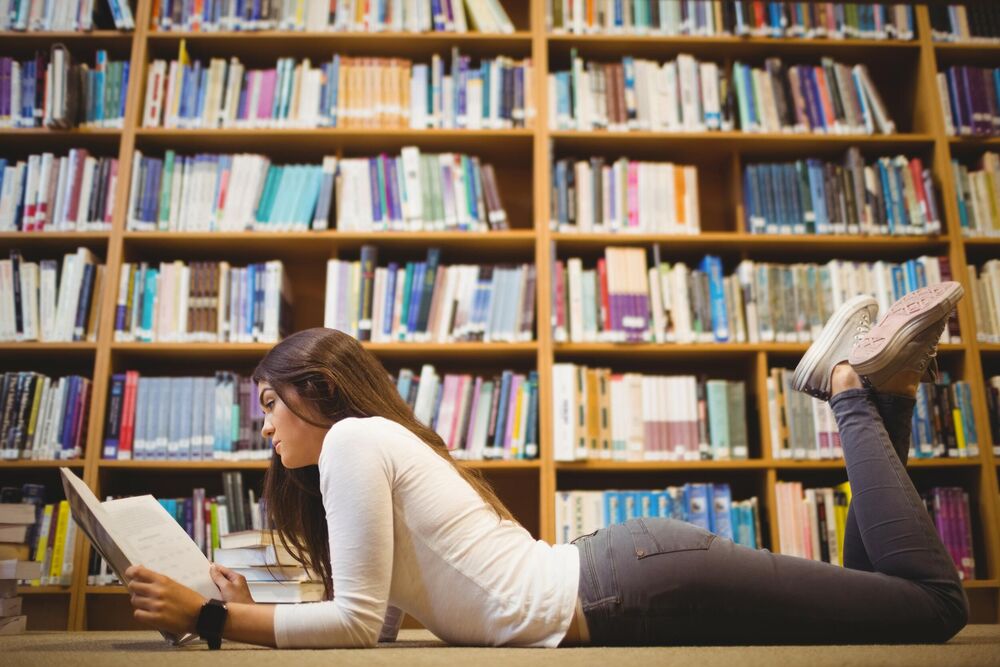 Devojka čita knjigu u biblioteci