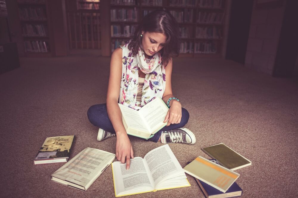 Devojka čita knjige u biblioteci / Ilustracija