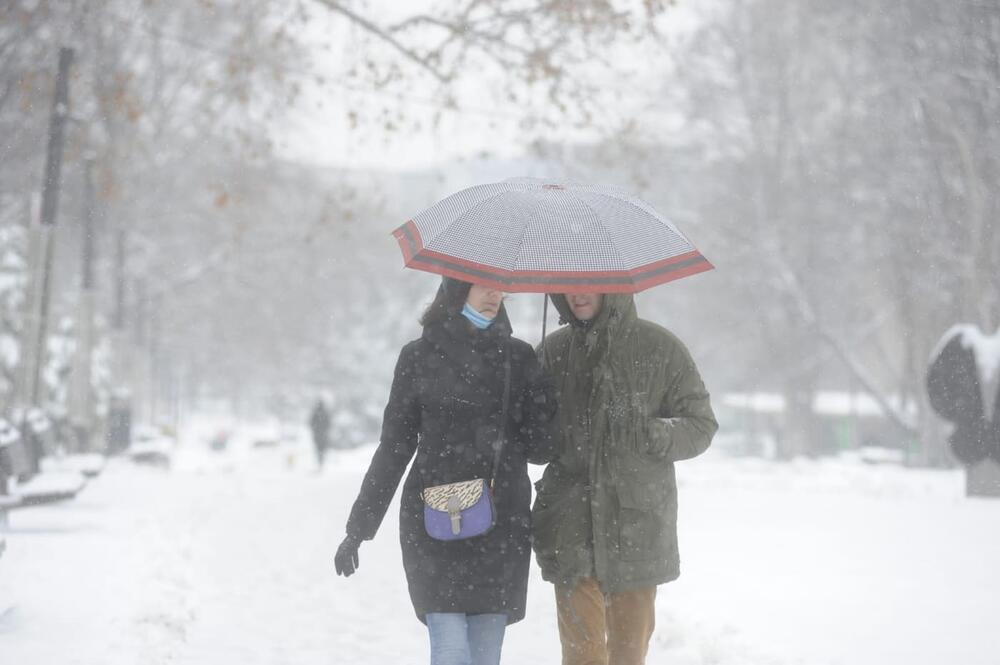 Par sa kišobranom šeta po snegu 