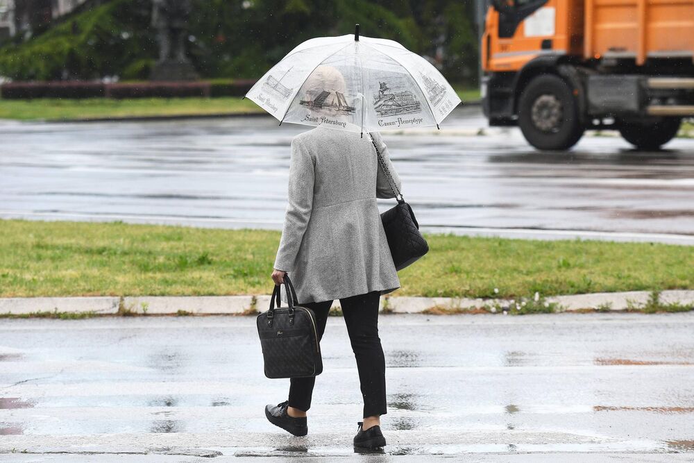 Žena u sivom kaputu sa kišobranom 